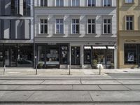 a store front next to a two car street with a bench in front of it