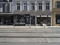 a store front next to a two car street with a bench in front of it