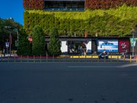 a street that has green walls and people on the side of it and two buildings