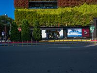 a street that has green walls and people on the side of it and two buildings