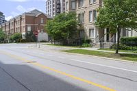 a city street lined with older brick apartment buildings near green shrubs and fenced green lawns