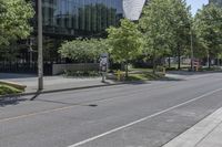 a city street with several trees lined on the side of it and a white traffic sign above