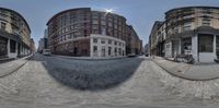 a 360 view lens of a cobbled down street and buildings in the middle of the day