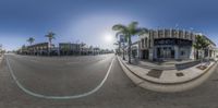 a street view from a fish eye lens with a blue sky and palm trees in the background