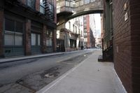 an alley way with people walking along and two cars in the street and buildings behind