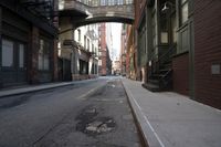 an alley way with people walking along and two cars in the street and buildings behind