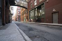 an alley way with people walking along and two cars in the street and buildings behind