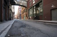an alley way with people walking along and two cars in the street and buildings behind