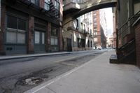 an alley way with people walking along and two cars in the street and buildings behind