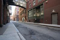 an alley way with people walking along and two cars in the street and buildings behind