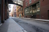 an alley way with people walking along and two cars in the street and buildings behind
