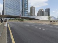 the view down the city street on an overpass near some tall buildings, with a yellow line on the middle of the road