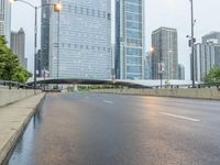 the view down the city street on an overpass near some tall buildings, with a yellow line on the middle of the road