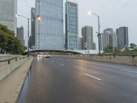 the view down the city street on an overpass near some tall buildings, with a yellow line on the middle of the road