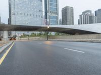 the view down the city street on an overpass near some tall buildings, with a yellow line on the middle of the road