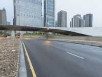 the view down the city street on an overpass near some tall buildings, with a yellow line on the middle of the road