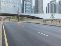 the view down the city street on an overpass near some tall buildings, with a yellow line on the middle of the road