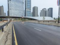 the view down the city street on an overpass near some tall buildings, with a yellow line on the middle of the road