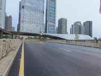 the view down the city street on an overpass near some tall buildings, with a yellow line on the middle of the road