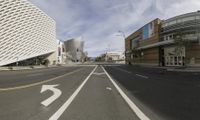 a view looking down a city street at an empty street with buildings and a white building