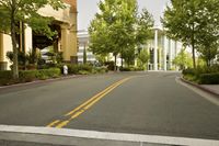 a street with two yellow lines going down it in an open area in front of a tall building