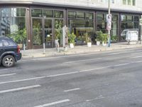 an empty street in front of a store on a street corner with tall windows and small cars