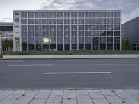 a street with cars passing by a long building and several windows in front of it