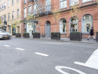 the cars are passing by the buildings on the street of the city streets as people walk near by