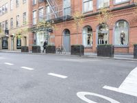 the cars are passing by the buildings on the street of the city streets as people walk near by