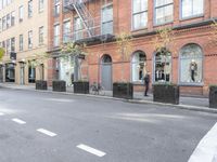 the cars are passing by the buildings on the street of the city streets as people walk near by