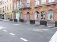 the cars are passing by the buildings on the street of the city streets as people walk near by
