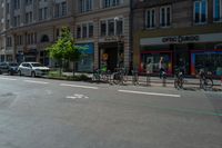 four bikes are on the street near a row of stores and cars and parked cars