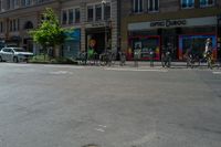 four bikes are on the street near a row of stores and cars and parked cars