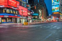 city street intersection with lights and buildings at night time in new york city, usa