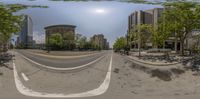 a view of a street through the lens of a panorama camera with a high rise building in the background