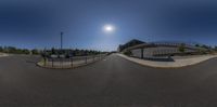 the sun sets behind the building and a skateboarder is performing stunts near a fence