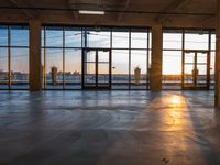 a room filled with glass windows and panes looking at the city at sunset during winter