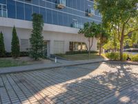 an apartment building with some glass windows and trees in the courtyard area of it to the sidewalk