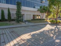 an apartment building with some glass windows and trees in the courtyard area of it to the sidewalk