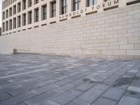 a person walking in the foreground on a stone pavement outside of a building, with a sign that reads umbold forum