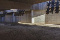 large concrete building with multiple vertical beams on it's walls, and another floor area to the left that has multiple small openings