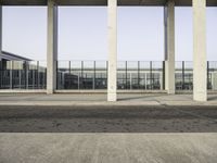 a man sitting on a bench in a parking lot near some glass windows in a building