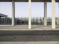 a man sitting on a bench in a parking lot near some glass windows in a building