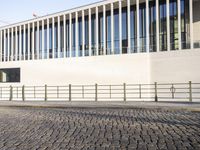 a person in the street riding on a skateboard in front of a building with multiple large windows