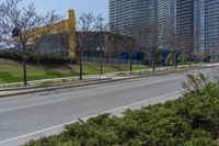 the side of a road has trees near by it and several buildings and a bicycle