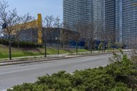 the side of a road has trees near by it and several buildings and a bicycle