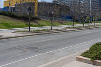 the side of a road has trees near by it and several buildings and a bicycle