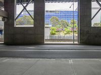 a view out of an outside walkway area in the city with large concrete columns and a bench