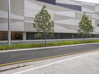 there is a street lined with parked cars and trees outside the building where there are empty parking spaces on the sides of the road