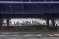 an empty parking lot is surrounded by two fenced off areas and a view of the city